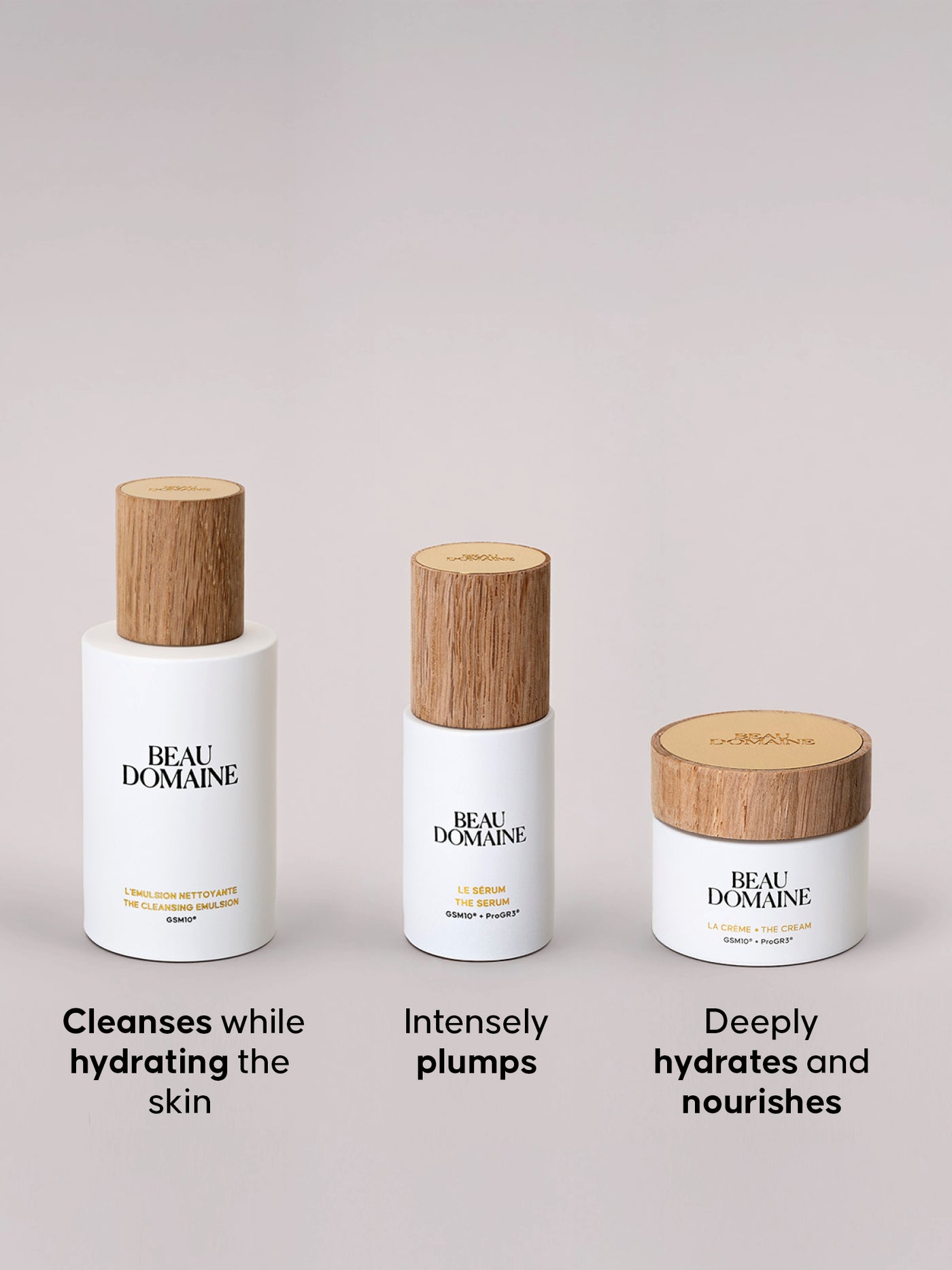 Três produtos de cuidado de pele da BEAU DOMAINE sobre fundo cinzento claro